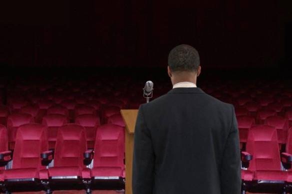 Mixed race businessman at podium in empty auditorium