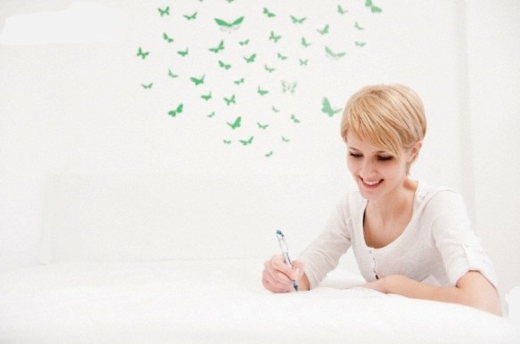 Young woman writing,sketching on bed